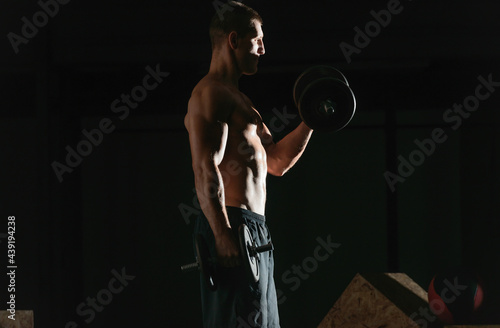 Side view of a bodybuilder doing heavy weight workout for biceps