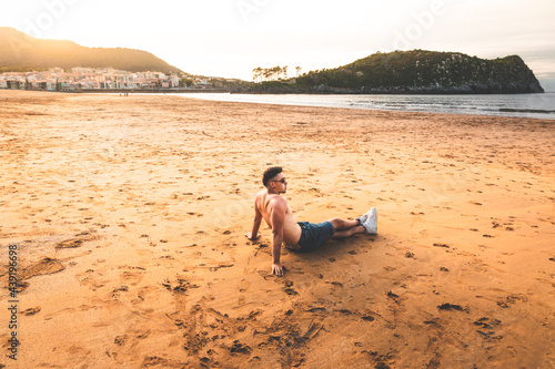 Young caucasian man sitting on the sand of a basque beach. photo