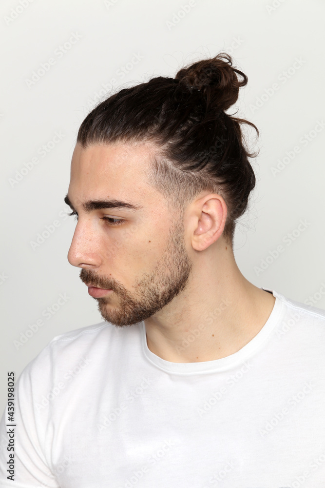 Obraz premium Attractive male model with long hair and beard posing in studio on isolated background. Style, trends, fashion concept.