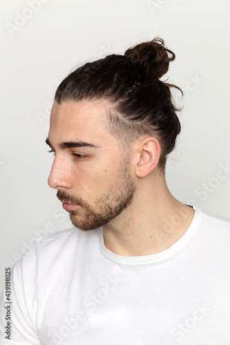 Attractive male model with long hair and beard posing in studio on isolated background. Style, trends, fashion concept.