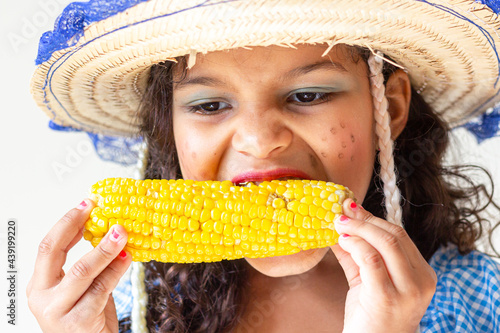 brazilian child eating corn  wearing traditional costume for Junina Party