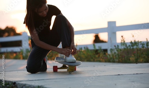 Young girl wearing facemask siting on surfboard to Tie her shoe preparing start exercie photo
