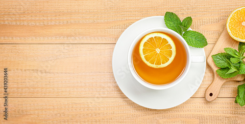 mug of tea with mint and lemon on a wooden background. view from above