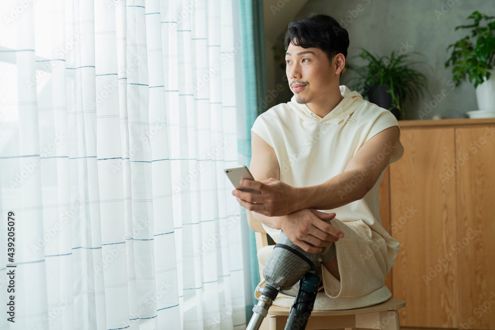 Fototapeta premium 窓際でスマートフォンを見る男性