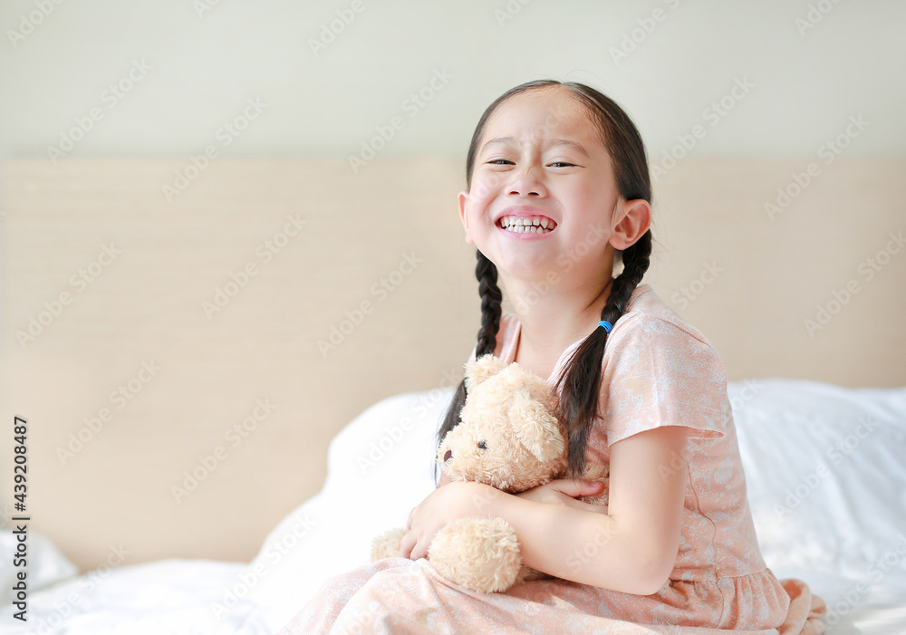 Happy Asian little child girl hugging teddy bear while sitting on the bed at home. Happy Asian little child girl hugging teddy bear while sitting on the bed at home.