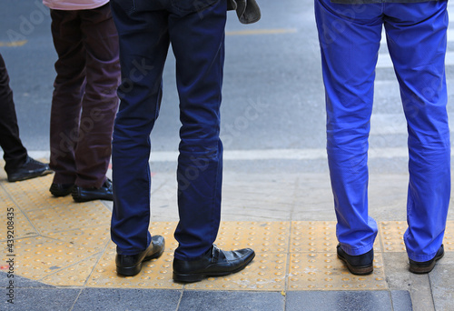 Legs of businessman waiting at the pedestrian crossing.