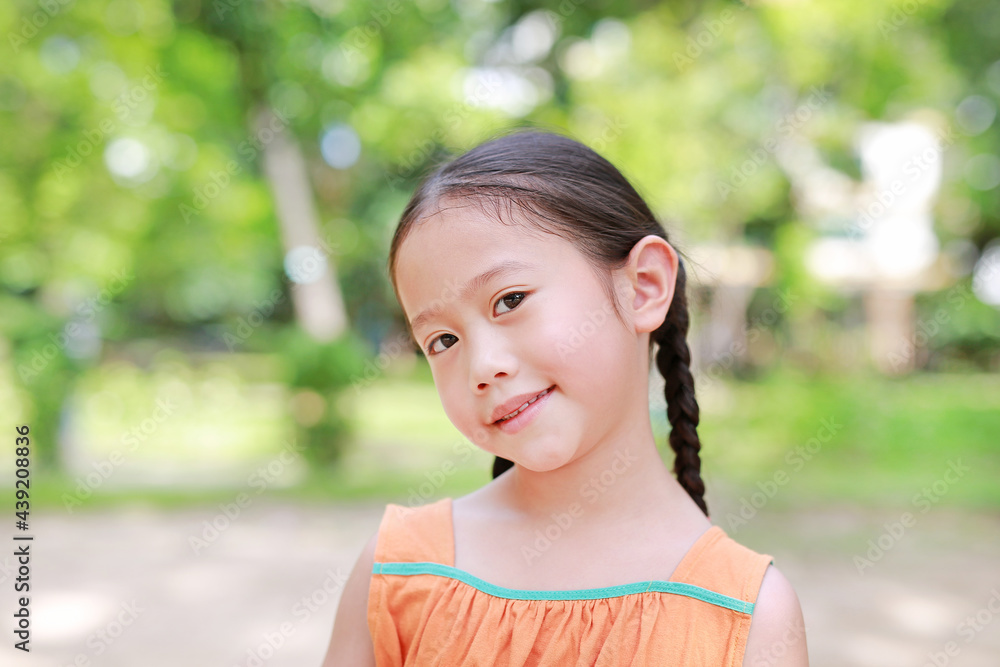 Portrait of happy little Asian child in green garden with looking at camera. Close up smiling kid girl in summer park. Portrait of happy little Asian child in green garden with looking at camera. Close up smiling kid girl in summer park.