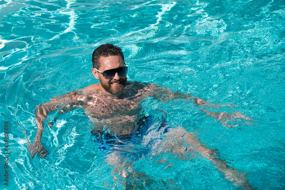 Summertime vacation at pool. Summer weekend. Handsome man in swimmingpool water. Pool spa resort.