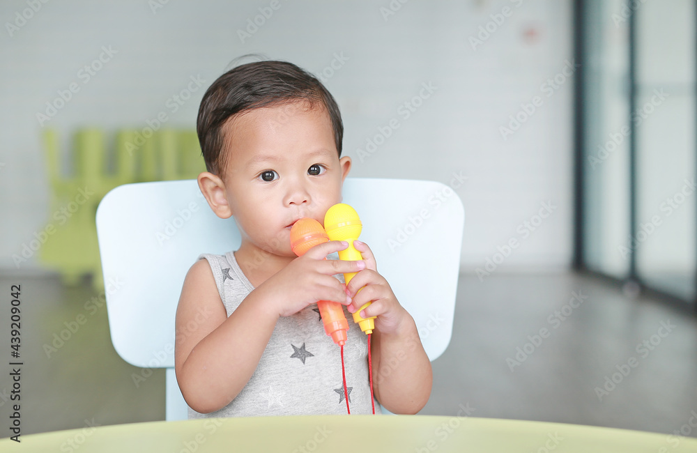 Portrait of little Asian baby boy sing a song by plastic microphone at children room. Portrait of little Asian baby boy sing a song by plastic microphone at children room.