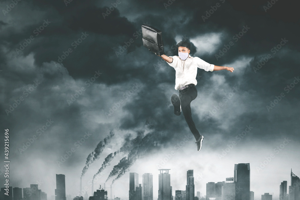 Businessman in face mask jumps above polluted city Businessman in face mask jumps above polluted city