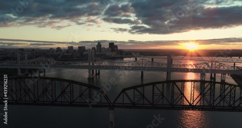 Downtown Louisville, Kentucky aerial sunset over Ohio River and Big Four Bridge.  Orange reflection and sun rays with wide shot of evening city skyline.