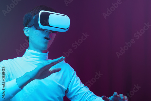 Excited asian young man wearing VR headset in neon light, Future technology concept.