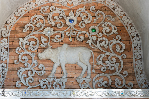  Stucco of a zodizac cow, classical Thai style on a temple wall.