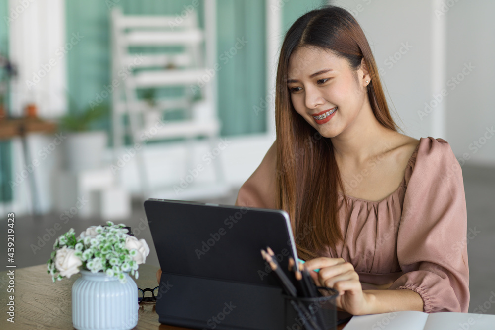 Happy female office worker working on digital tablet in office room Happy female office worker working on digital tablet in office room