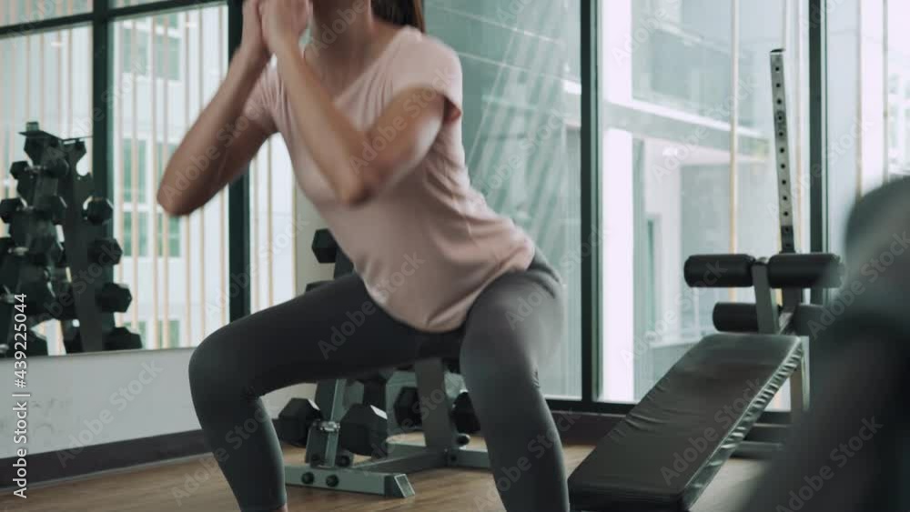 Woman exercising in fitness with squat for increase abdominal muscles. Woman is diet weight by exercising every day. A woman is exercising in the condo fitness area that is the area for condo buyers. Woman exercising in fitness with squat for increase abdominal muscles. Woman is diet weight by exercising every day. A woman is exercising in the condo fitness area that is the area for condo buyers.