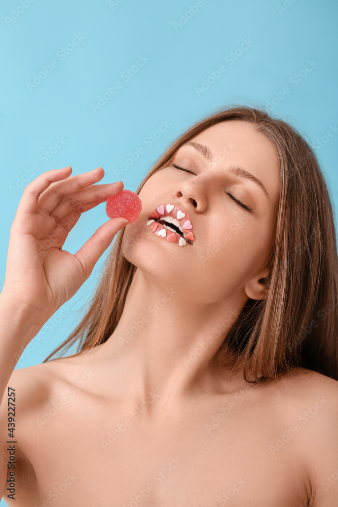 Beautiful young woman with creative makeup and candy on color background Beautiful young woman with creative makeup and candy on color background