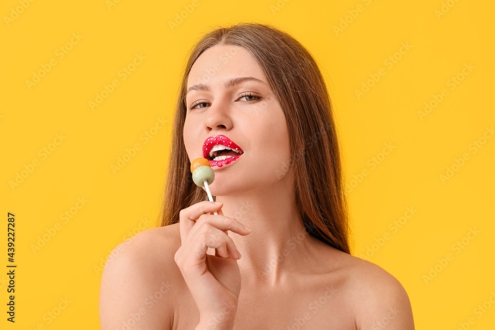 Beautiful young woman with creative makeup and sweet lollipop on color background Beautiful young woman with creative makeup and sweet lollipop on color background