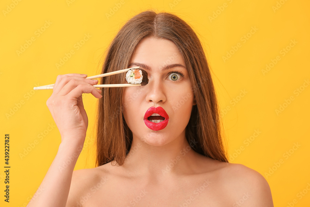 Obraz premium Surprised young woman with tasty sushi roll on color background