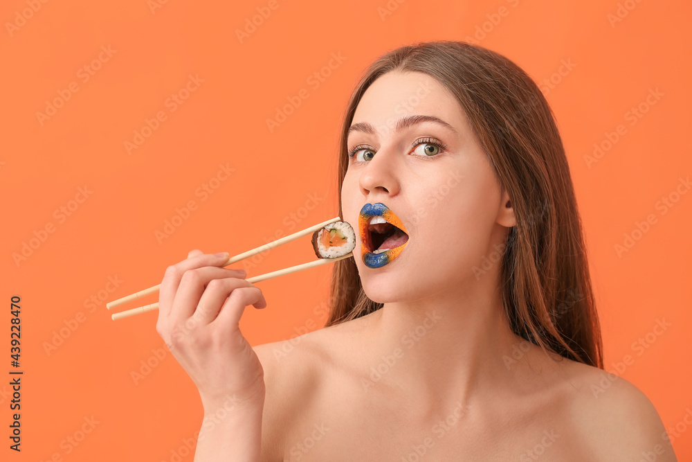 Beautiful young woman with creative makeup and tasty sushi roll on color background Beautiful young woman with creative makeup and tasty sushi roll on color background