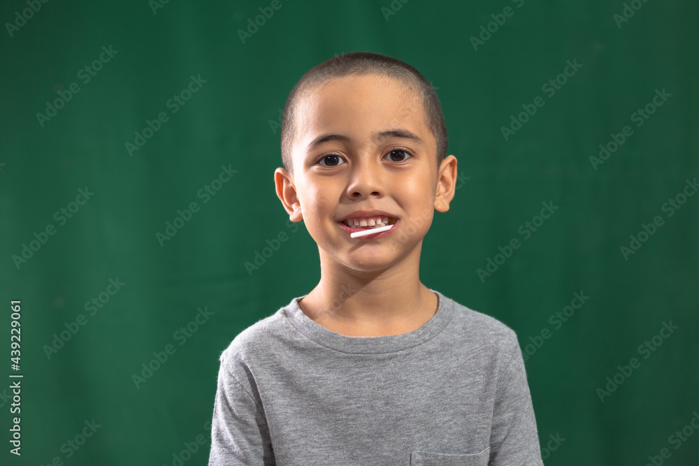 Cute caucasian young kid holding yellow lollipop showing broken milk tooth..Studio portrait, concept health with dark green background..boy in smiling face,cheeky face and funny posting. Cute caucasian young kid holding yellow lollipop showing broken milk tooth..Studio portrait, concept health with dark green background..boy in smiling face,cheeky face and funny posting.