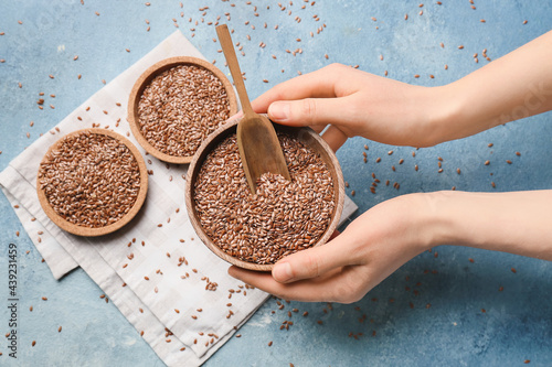 Female hands with bowl of flax seeds on color background photo