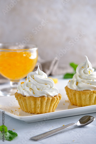 Tartlets with orange jam and protein cream decorated with orange zest on a white plate