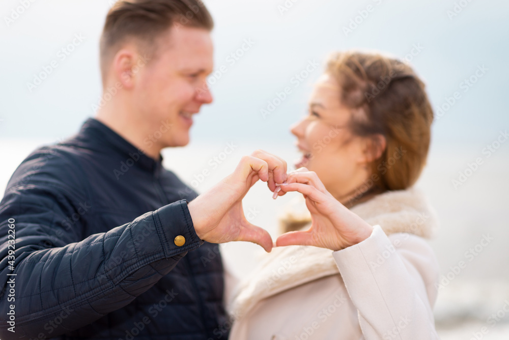Two young couple is making heart, looking at each other and smiling while standing at the beach. Two young couple is making heart, looking at each other and smiling while standing at the beach.
