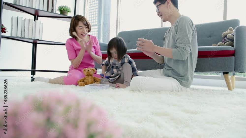 Slow motion of happy cheerful asian family of three father mother little daugther sitting on carpet at home clapping and cheering her daugther while playing with toys. Slow motion of happy cheerful asian family of three father mother little daugther sitting on carpet at home clapping and cheering her daugther while playing with toys.