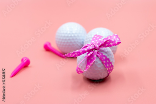 Golf ball with pink ribbon are on pink background