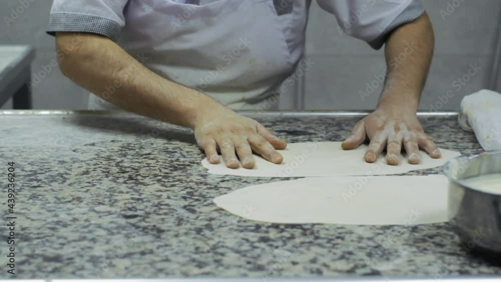 Chef putting flatbread dough on prep-table. 4K in slow motion.