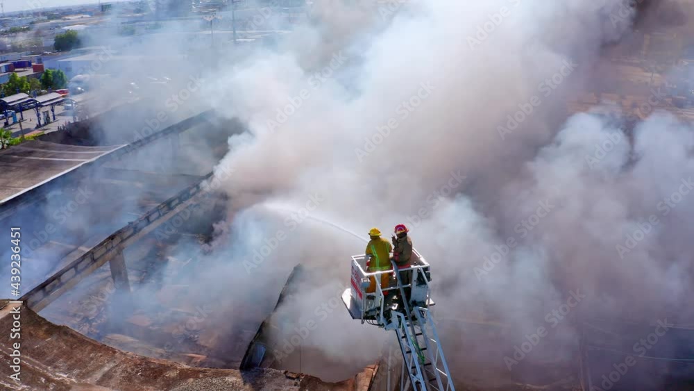 Firefighters on hydraulic crane platform over La Reina mattress factory destroyed by fire. Aerial
