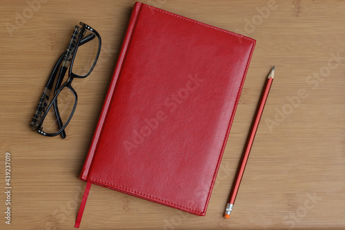 Pen with a business notebook on a wooden table background and glasses for vision
