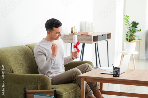 Happy male student on his graduation day at home. Concept of online education