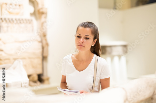 Portrait of young woman with guide brochure observing sculptures exposition in art museum Free Download Portrait of young woman with guide brochure observing sculptures exposition in art museum - GFXLoad