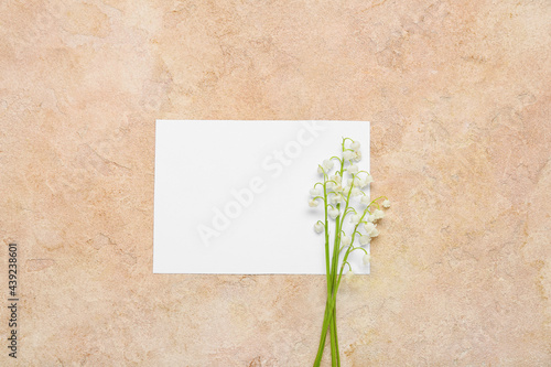 Beautiful lily-of-the-valley flowers and blank card on color background