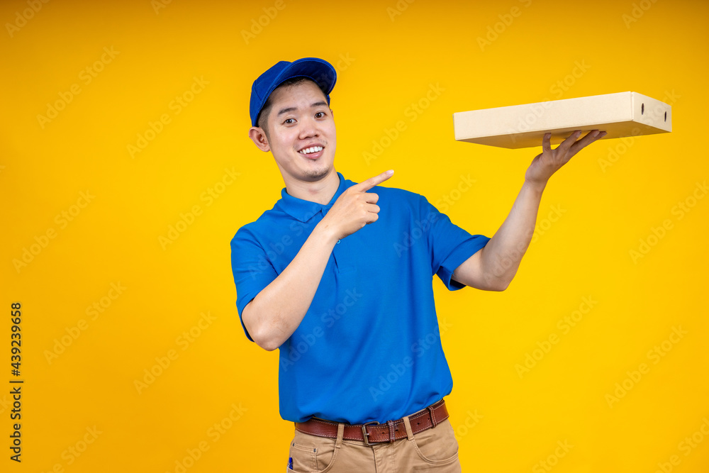 Asian delivery man holding pizza or parcel box over yellow isolate background. Work from home and delivery concept. Asian delivery man holding pizza or parcel box over yellow isolate background. Work from home and delivery concept.