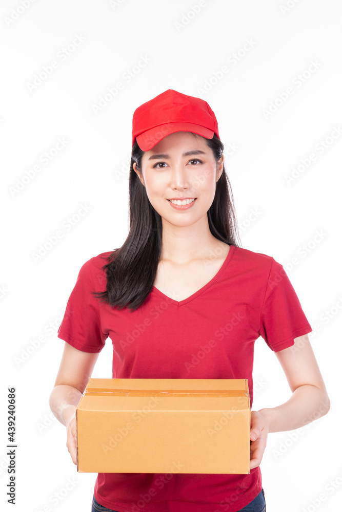 Delivery young female in red uniform on white background. Female in red doing delivery courier working. Beautiful delivery woman carrying cardboard box. Attractive delivery woman. Delivery young female in red uniform on white background. Female in red doing delivery courier working. Beautiful delivery woman carrying cardboard box. Attractive delivery woman.