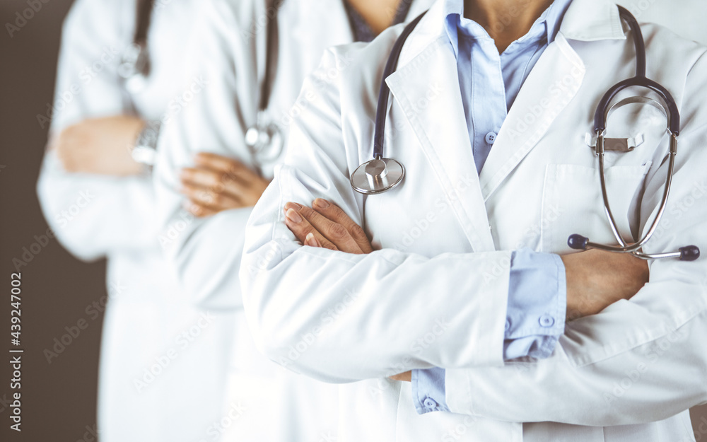 Group of modern doctors standing as a team with arms crossed in hospital office and ready to help patients. Medical help, insurance in health care, best disease treatment and medicine concept Group of modern doctors standing as a team with arms crossed in hospital office and ready to help patients. Medical help, insurance in health care, best disease treatment and medicine concept