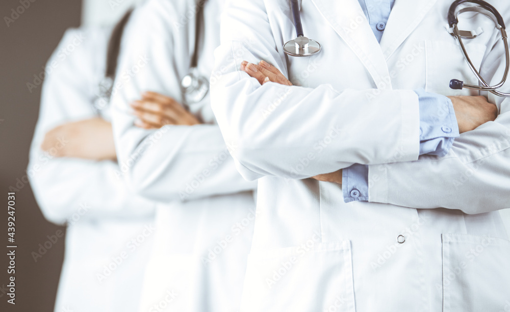 Group of modern doctors standing as a team with arms crossed in hospital office and ready to help patients. Medical help, insurance in health care, best disease treatment and medicine concept Group of modern doctors standing as a team with arms crossed in hospital office and ready to help patients. Medical help, insurance in health care, best disease treatment and medicine concept