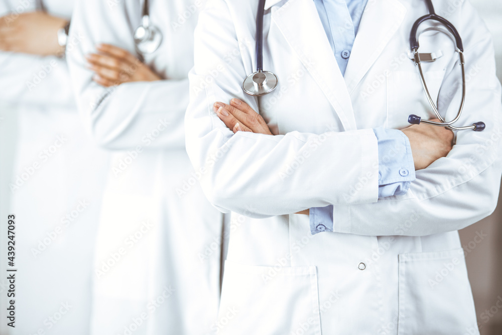 Group of modern doctors standing as a team with arms crossed in hospital office and ready to help patients. Medical help, insurance in health care, best disease treatment and medicine concept Group of modern doctors standing as a team with arms crossed in hospital office and ready to help patients. Medical help, insurance in health care, best disease treatment and medicine concept