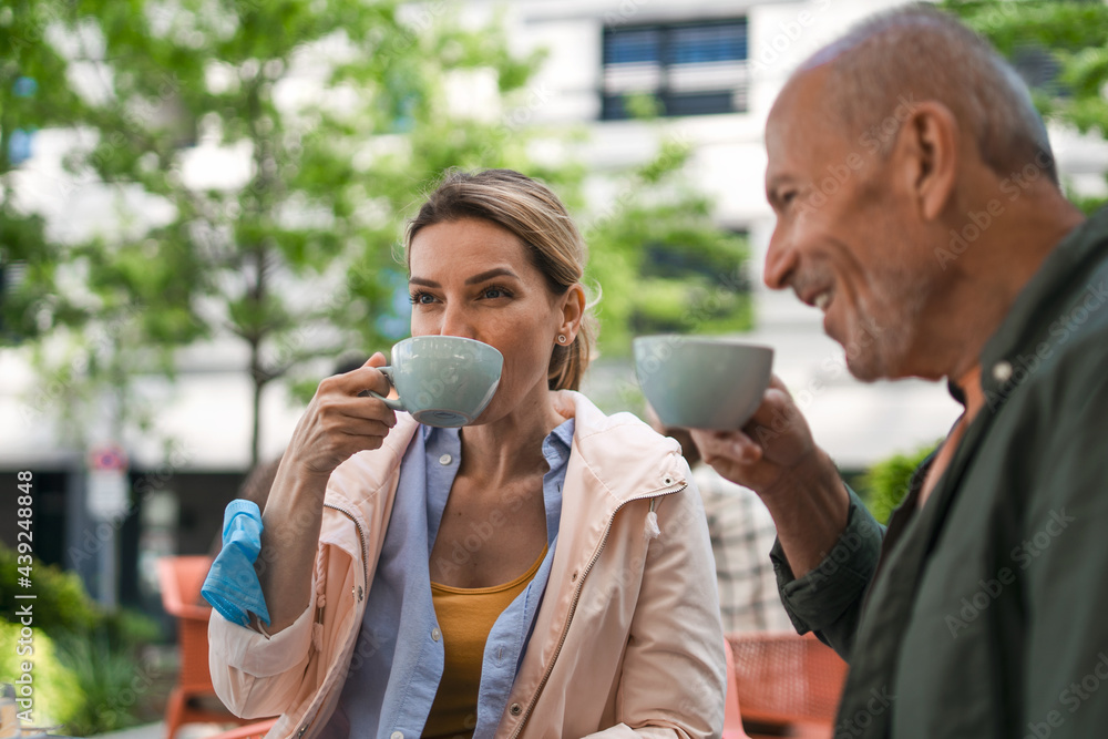 Woman with senior father in cafe outdoors in city, life after covid-19 vaccination and back to normal concept. Woman with senior father in cafe outdoors in city, life after covid-19 vaccination and back to normal concept.