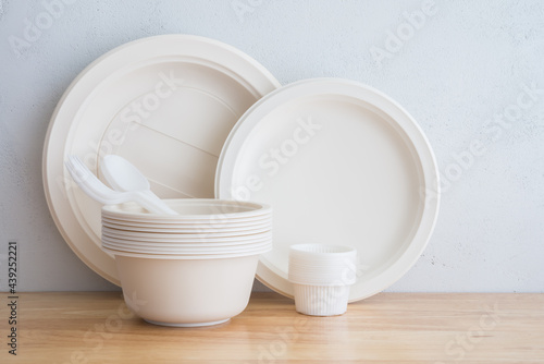 Quadro su tela Natural eco-friendly disposable utensils (fork, spoon, dish plate, bowl) made of fiber of bagasse and bamboo on wooden table with white wall background