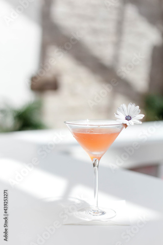 Summer cocktail garnished with flowers. Cold alcohol beverage on bar