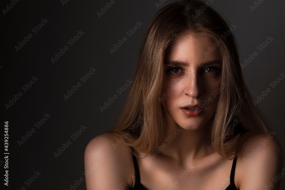 Portrait of Passionate Caucasian Blond Girl With Long Beautiful Hair Posing Against Dark Background. Portrait of Passionate Caucasian Blond Girl With Long Beautiful Hair Posing Against Dark Background.