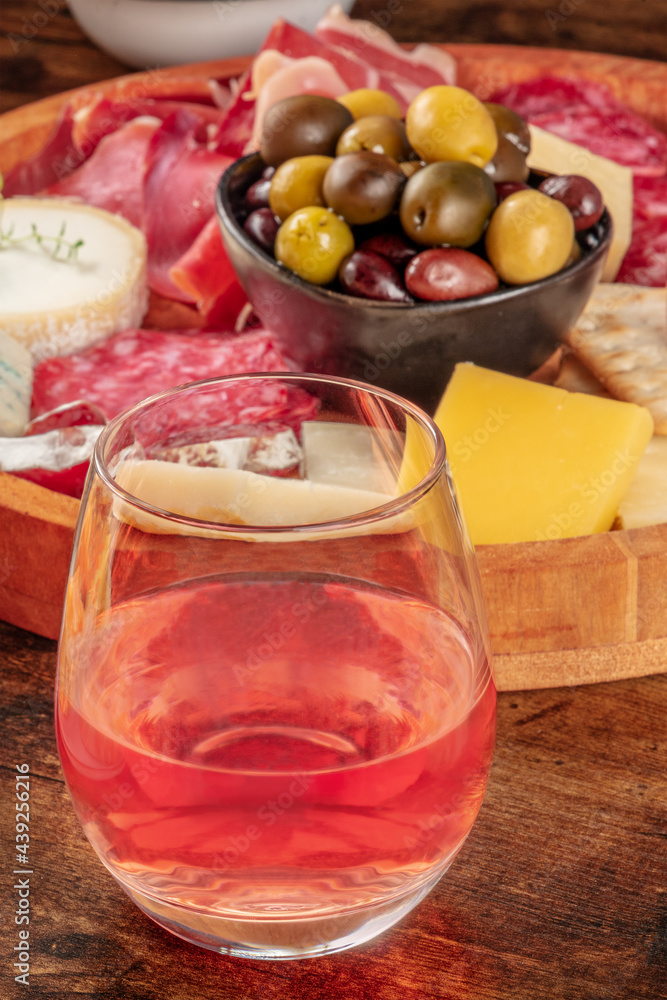 A glass of rose wine,close-up in front of a cheese board with olives. A drink in a bar with antipasti or tapas. Gourmet food A glass of rose wine,close-up in front of a cheese board with olives. A drink in a bar with antipasti or tapas. Gourmet food