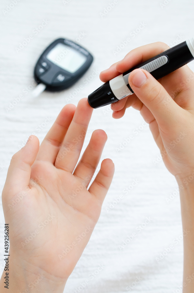 Diabetes checking blood sugar level. Child using lancelet and glucometer at home Diabetes checking blood sugar level. Child using lancelet and glucometer at home