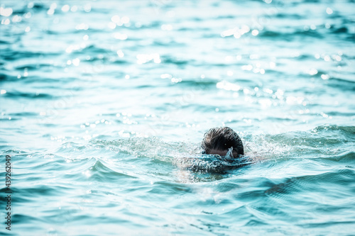 Head of a man swimming breaststroke in the sea. Minimalist plot