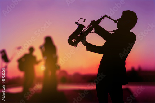 Silhouette twilight scene of Saxophone man showing as trio musicians. Background for celebrate party or autumn and summer festival.