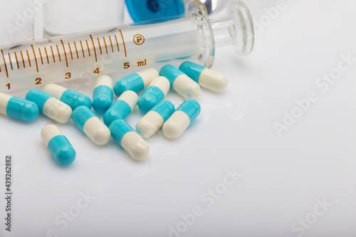 Many capsule pills and drug Syringe on white background