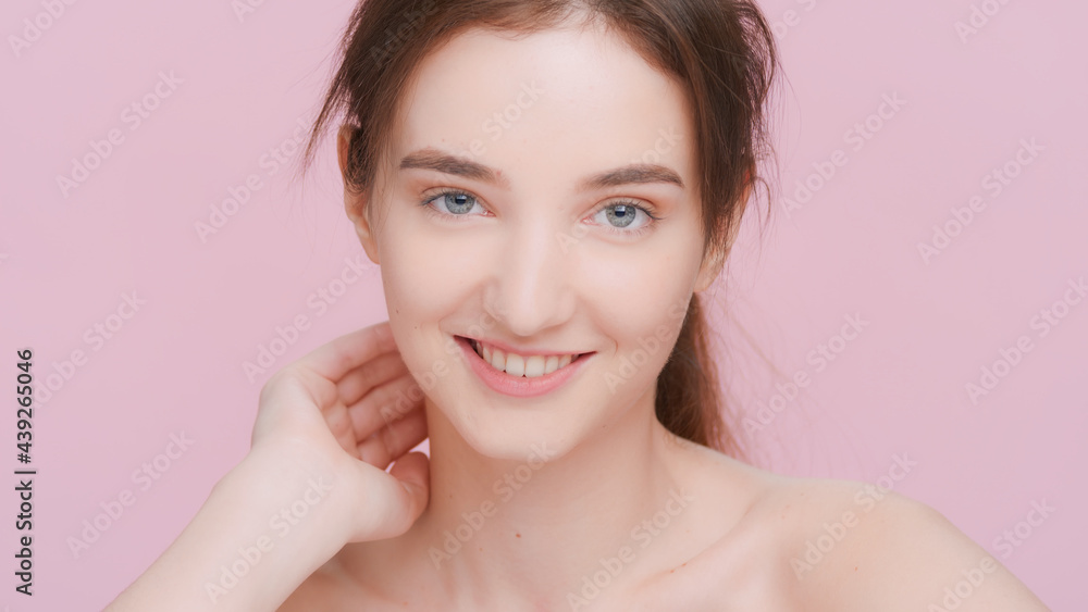 Young brown-haired woman looks at the camera and gently touches her face, sliding fingers from the cheek, behind the ear and down to the neck | skin care product advertising concept. Young brown-haired woman looks at the camera and gently touches her face, sliding fingers from the cheek, behind the ear and down to the neck | skin care product advertising concept.